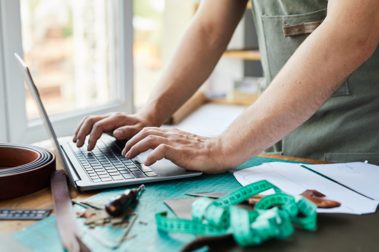 Handwerker arbeitet in seiner Werkstatt am Laptop